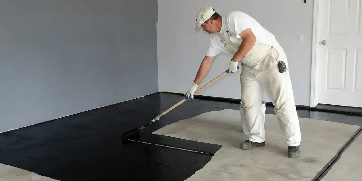 basement waterproofing professional applying waterproof coating to protect a basement floor in Aurora, CO